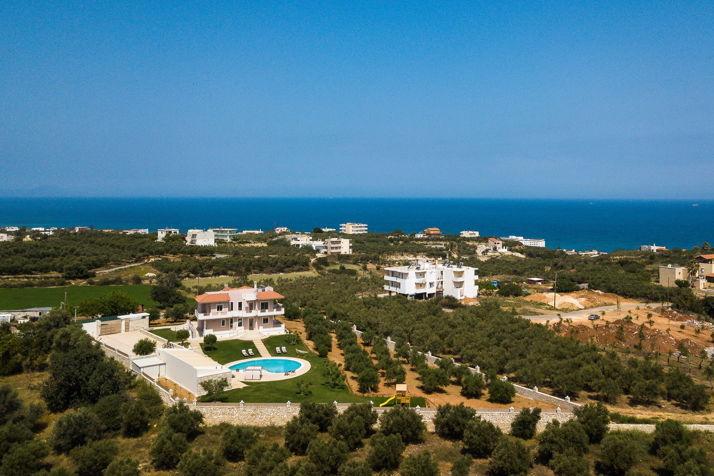 Aerial view of Aelia Residence among olive groves near the Cretan coast