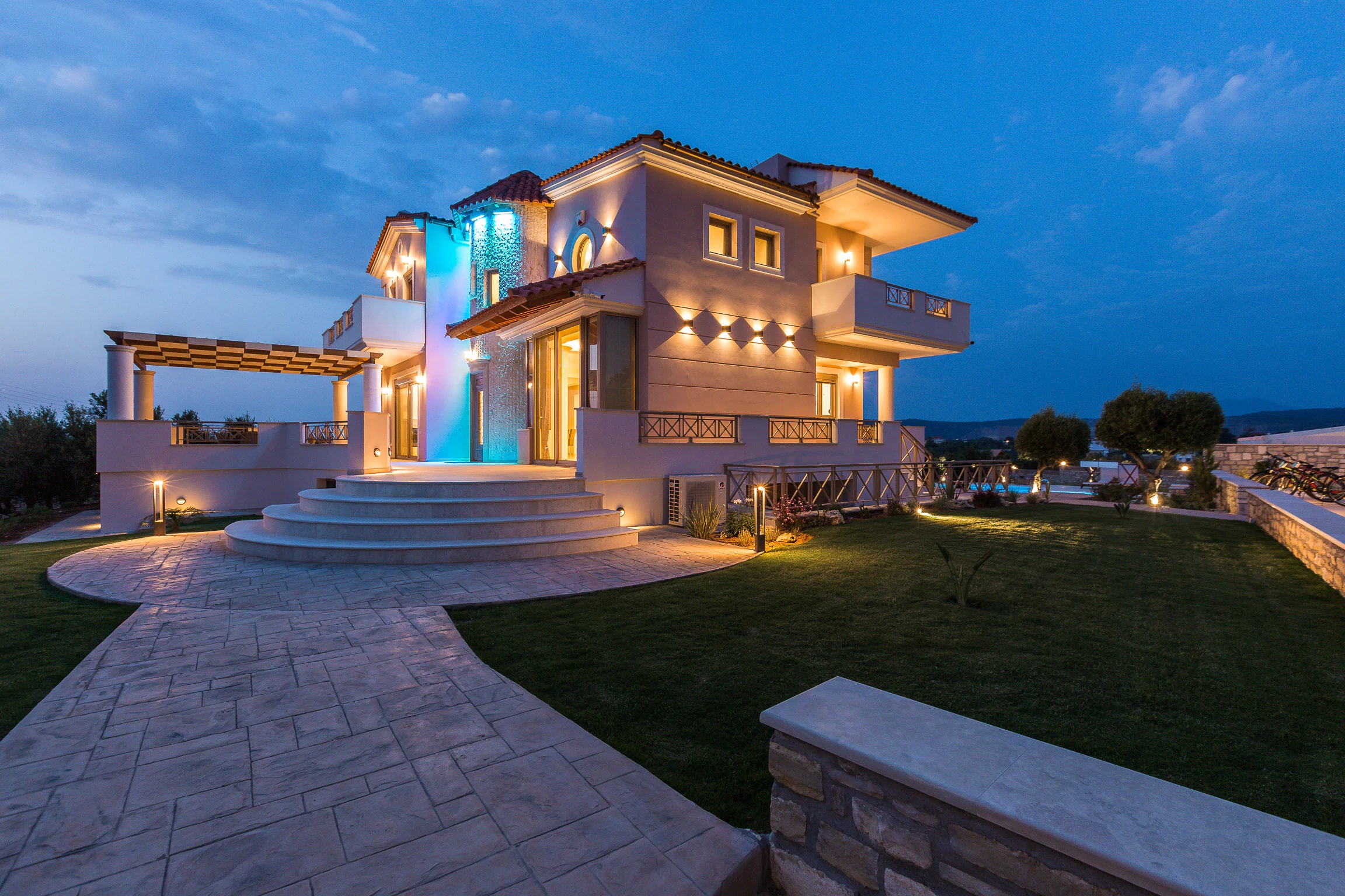 Illuminated residence reflected in the pool after sunset